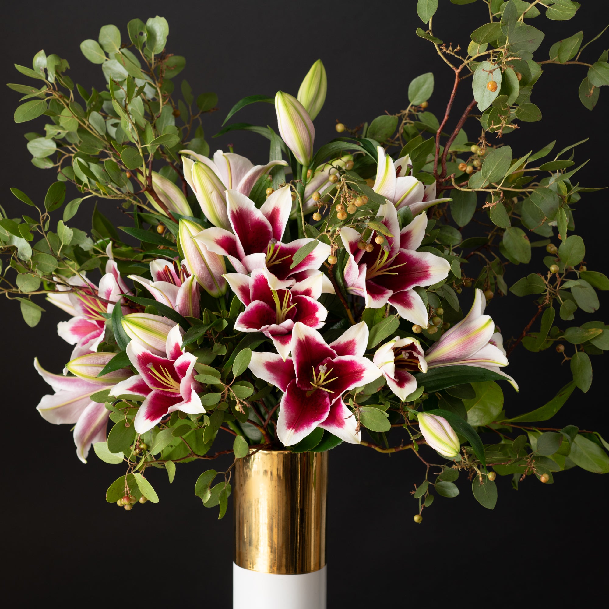 Elegant stargazer lily floral arrangement with lush greenery and sculptural accents, showcasing Bloom by Anuschka’s expert flower crafting.