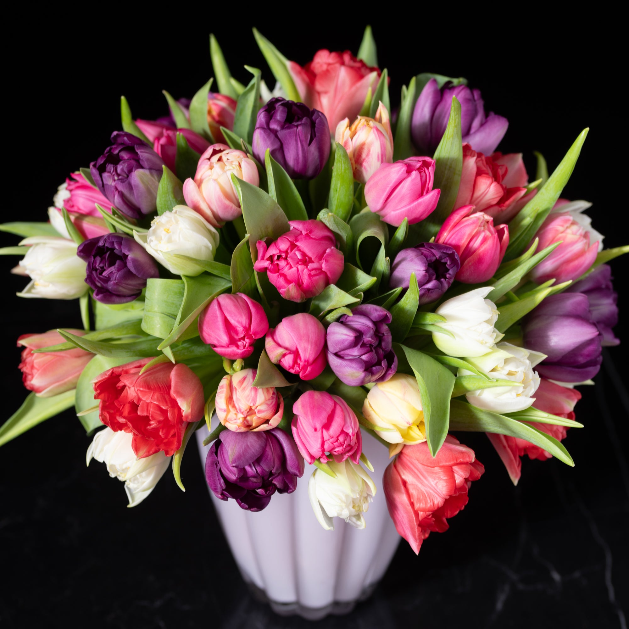 Mixed specialty tulips in a range of bright colors with lush green foliage designed by Bloom by Anuschka showcasing expert flower crafting.