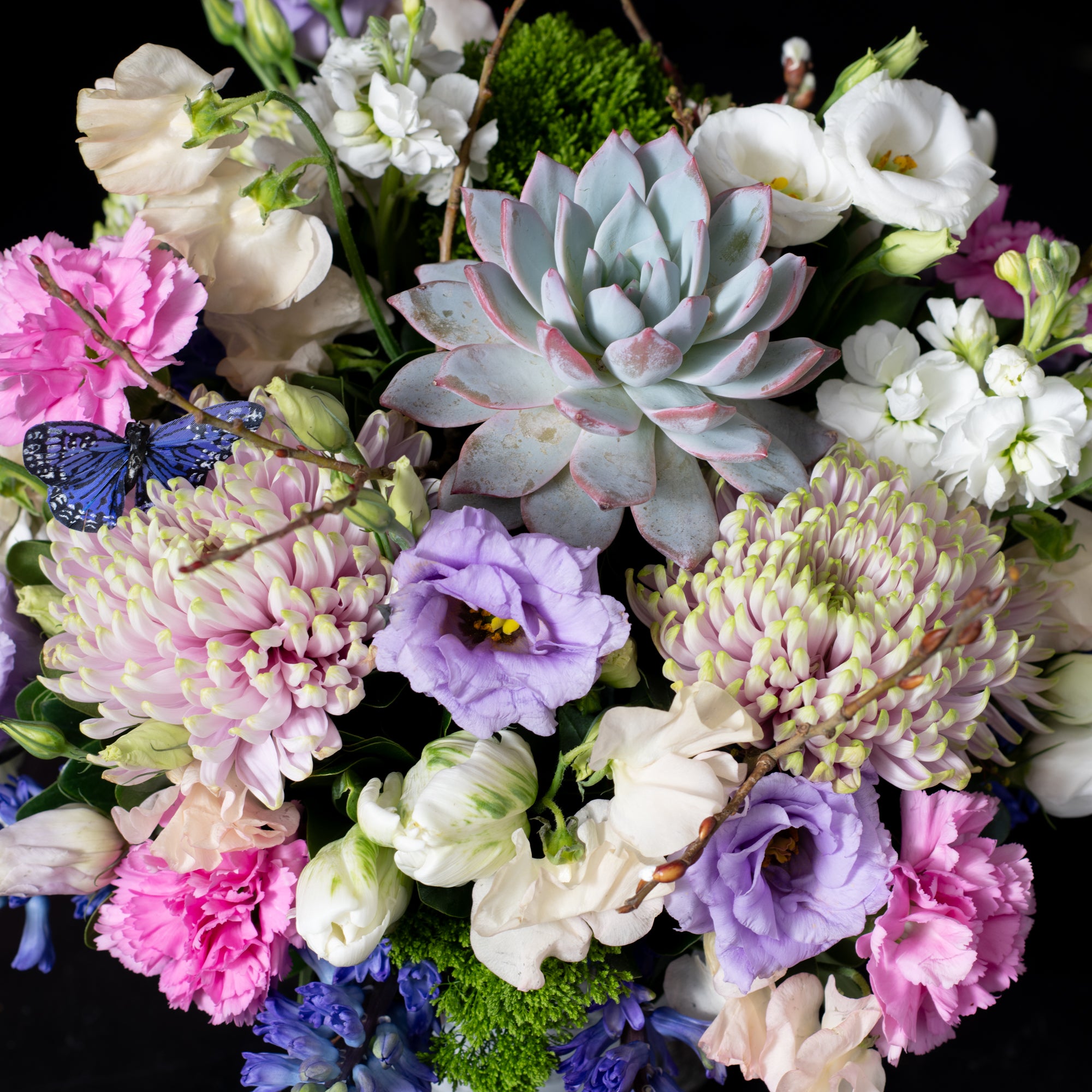 Whimsical floral design featuring lisianthus, carnations, and succulents, arranged in a rustic birch vase by Denver’s premier florist shop