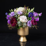 Lavish purple, burgundy, and lavender flowers in a gold pedestal vase, showcasing Bloom by Anuschka’s upscale Cherry Creek florist artistry.