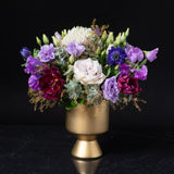Lavish purple, burgundy, and lavender flowers in a gold pedestal vase, showcasing Bloom by Anuschka’s upscale Cherry Creek florist artistry.