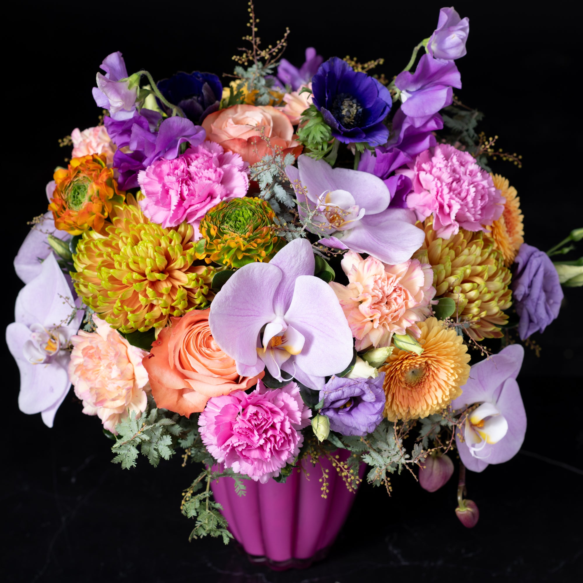 A stunning mixed flower arrangement in a striking pink vase featuring lisianthus daisies and orchids expertly crafted by Bloom by Anuschka a premier Denver flower shop
