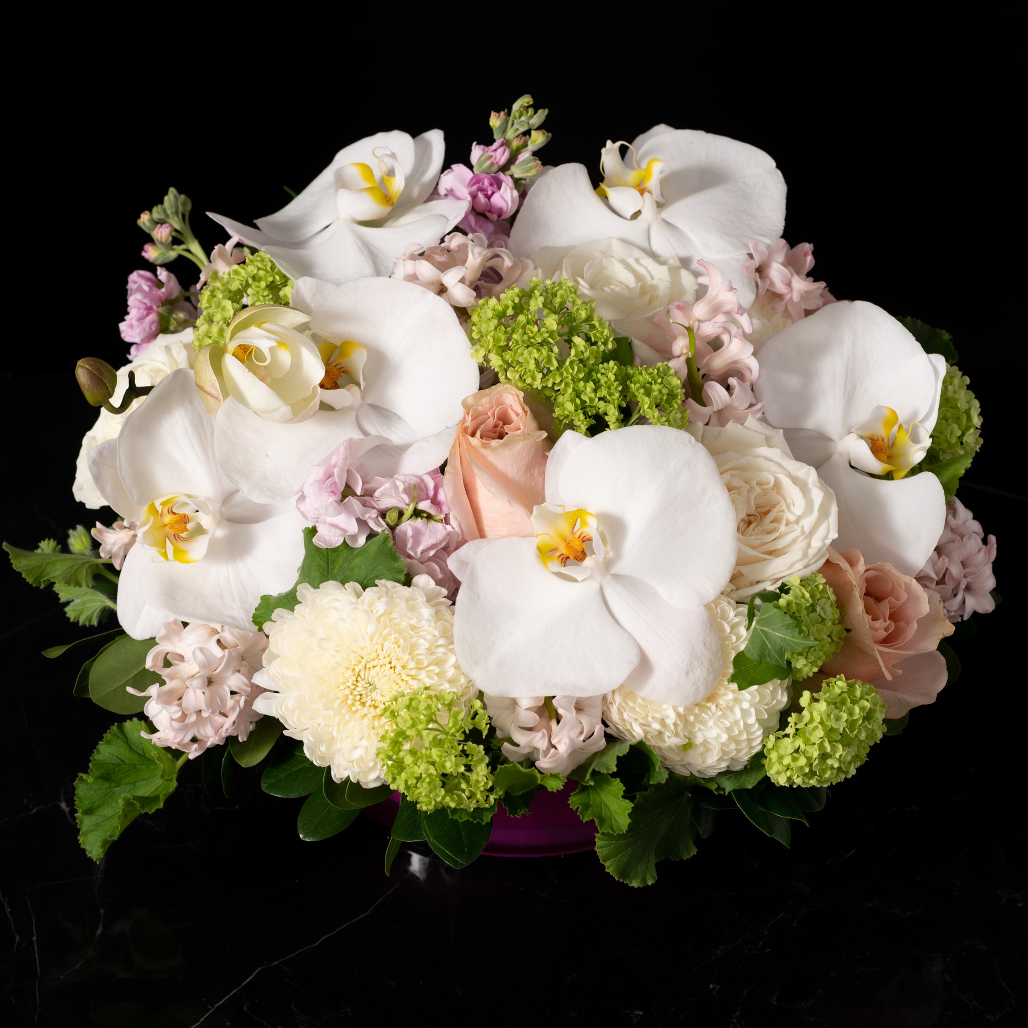 Elegant orchid and rose arrangement with soft pastel blooms and lush greenery, showcasing Bloom by Anuschka’s expert flower crafting and floral artistry.