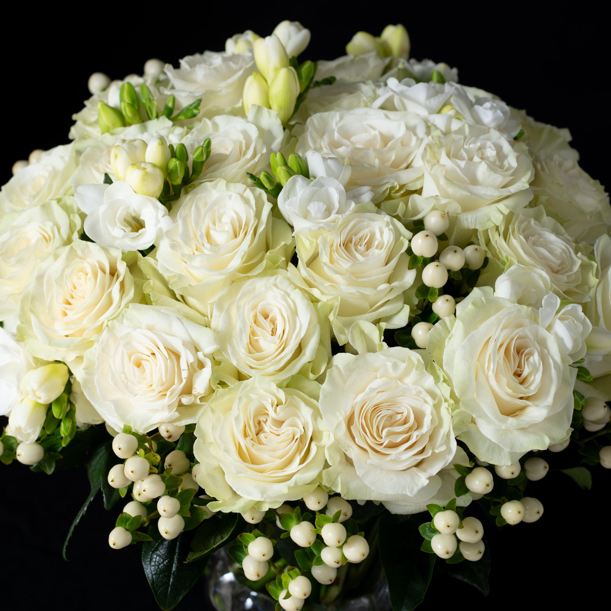 White roses, freesia, and hypericum berries arranged by Bloom by Anuschka in a pedestal vase, showcasing the artistry of florist’s design.