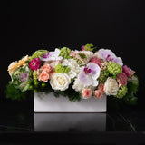 Arrangement of pink orchids, peach roses, and soft hydrangeas by Bloom by Anuschka, showcasing the artistry of flower crafting.