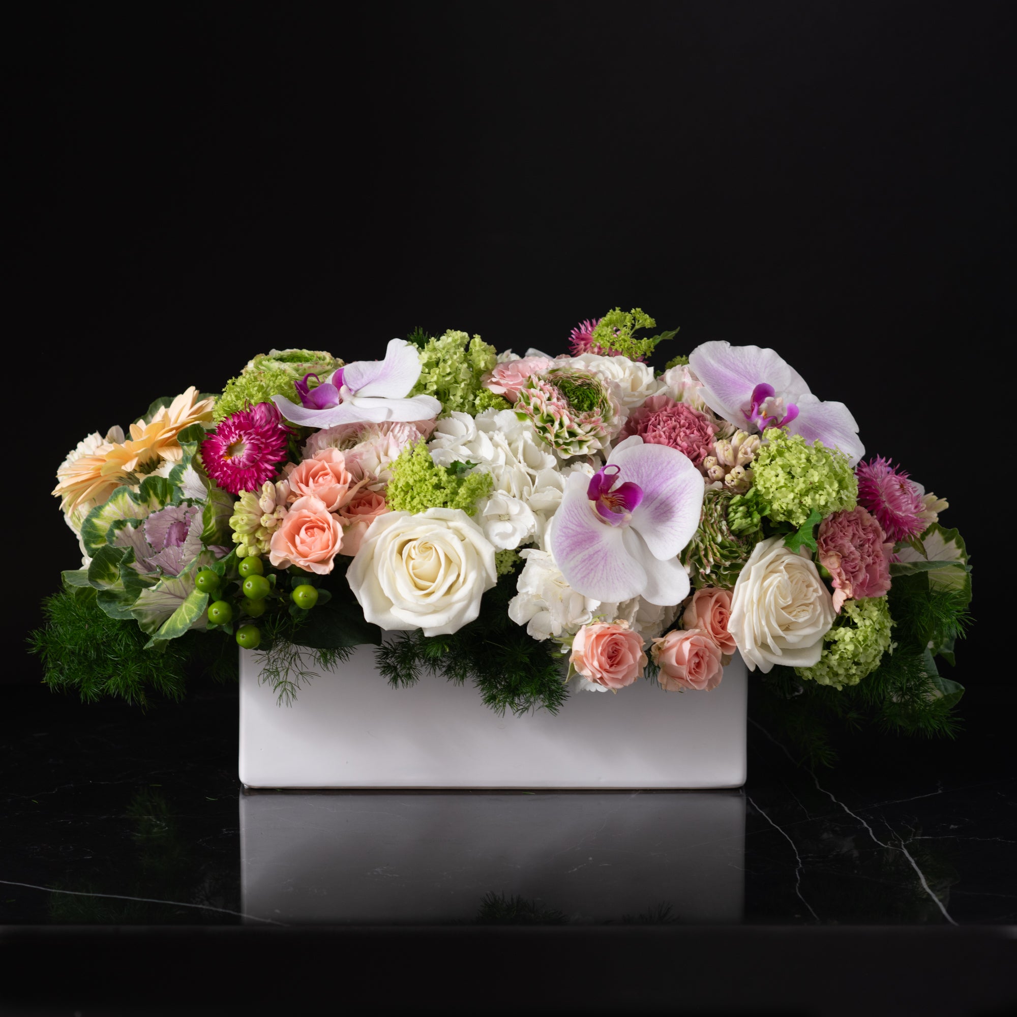Arrangement of pink orchids, peach roses, and soft hydrangeas by Bloom by Anuschka, showcasing the artistry of flower crafting.