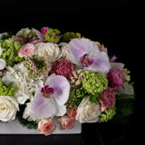 Close-up of delicate orchids, roses, and complementary flowers elegantly arranged by Bloom by Anuschka in a modern box, exemplifying a leading flower business.