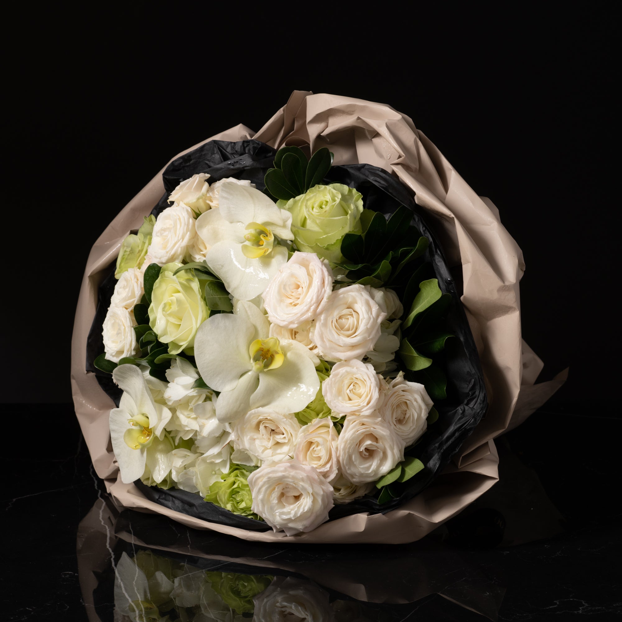 Elegant white floral bouquet with soft roses, orchids, and lush greenery, showcasing Bloom by Anuschka’s expert flower crafting and floral artistry.